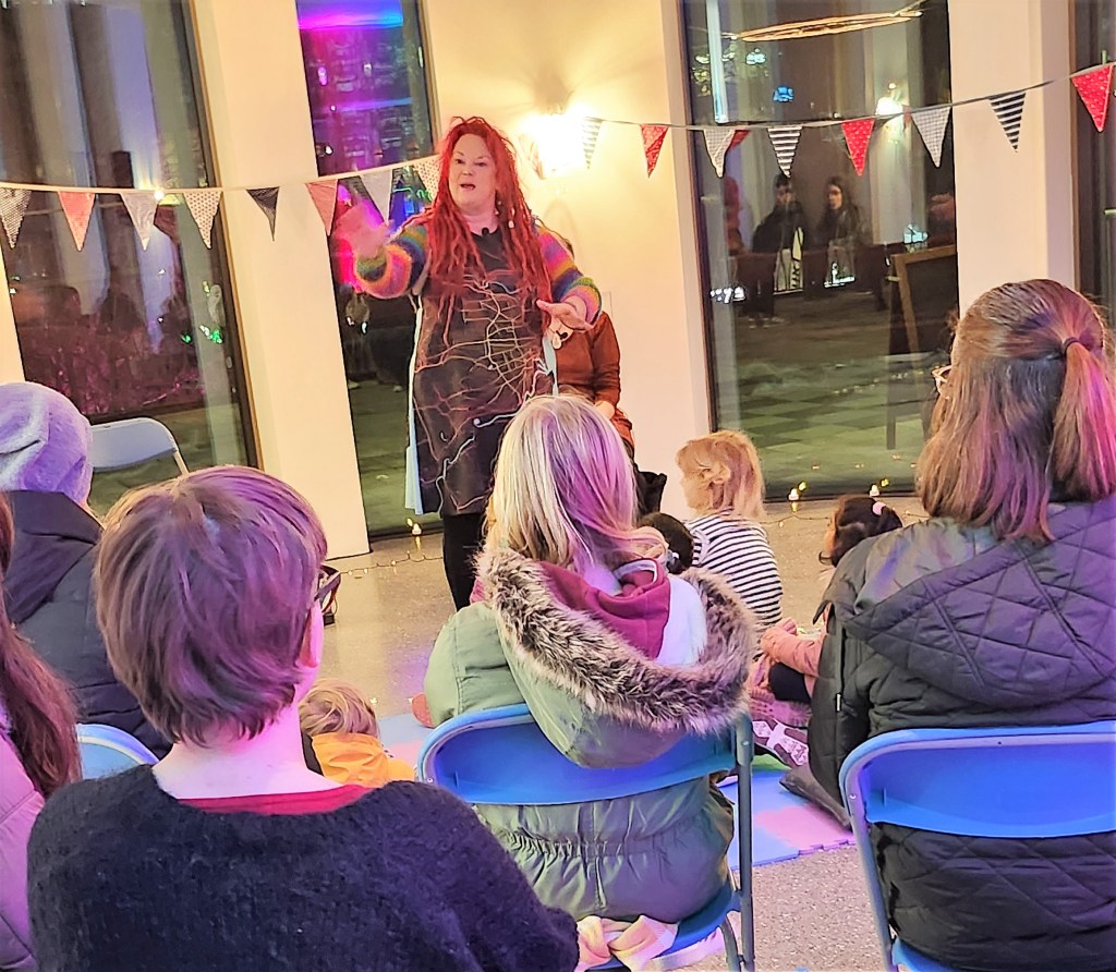 Pauline Cordiner and Lindsey Gibb tell stories at Spectra Light Festival 2023.
Pauline looks into the crowd and gestures. 